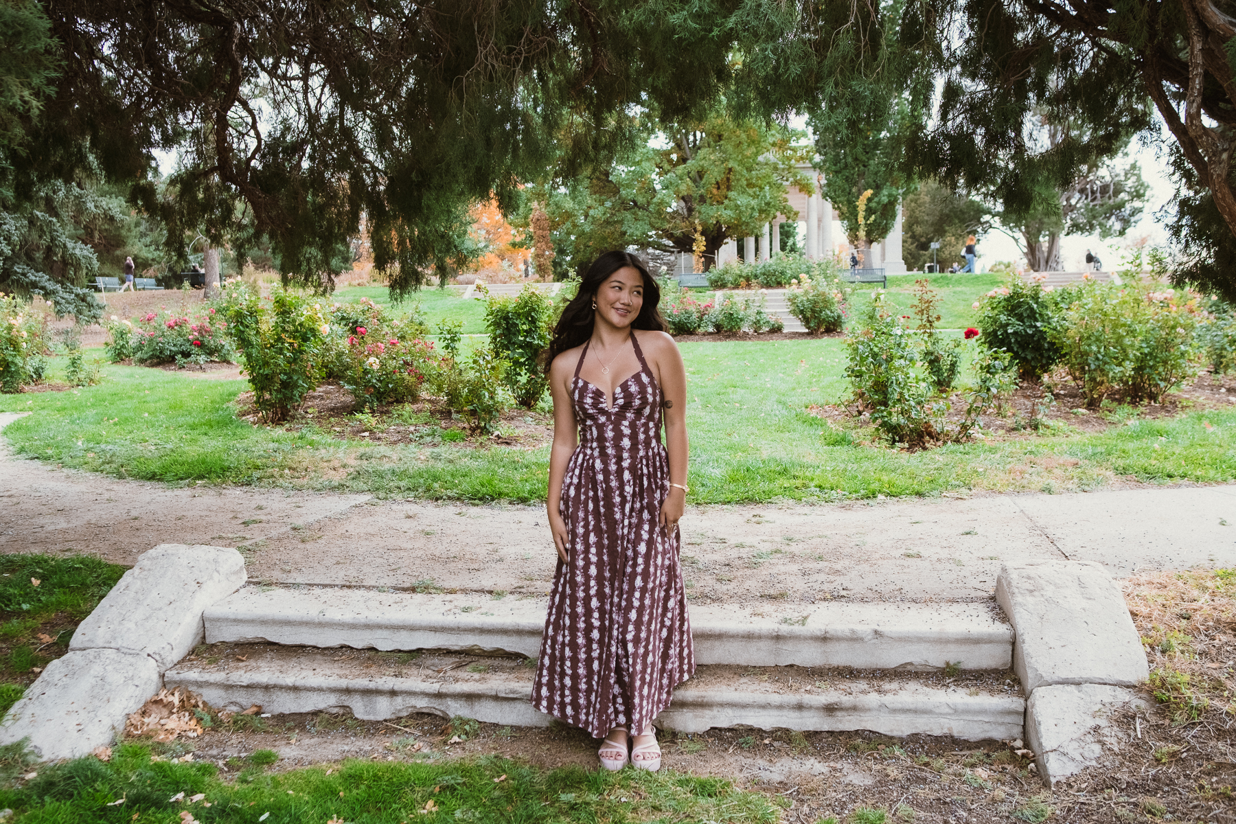 Young woman posing gracefully in a garden by stone steps